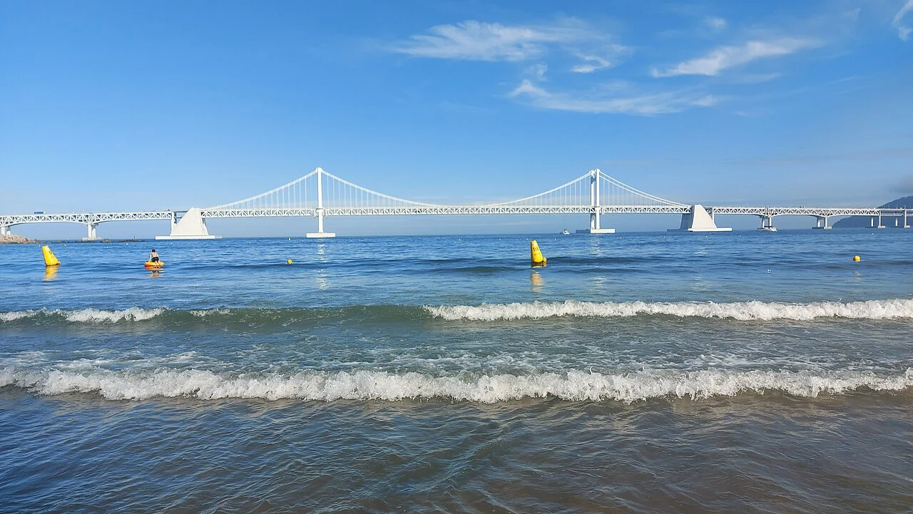 白天從廣安里海灘正面看向廣安大橋與海面，顯示海灘寬度與主要觀賞方向